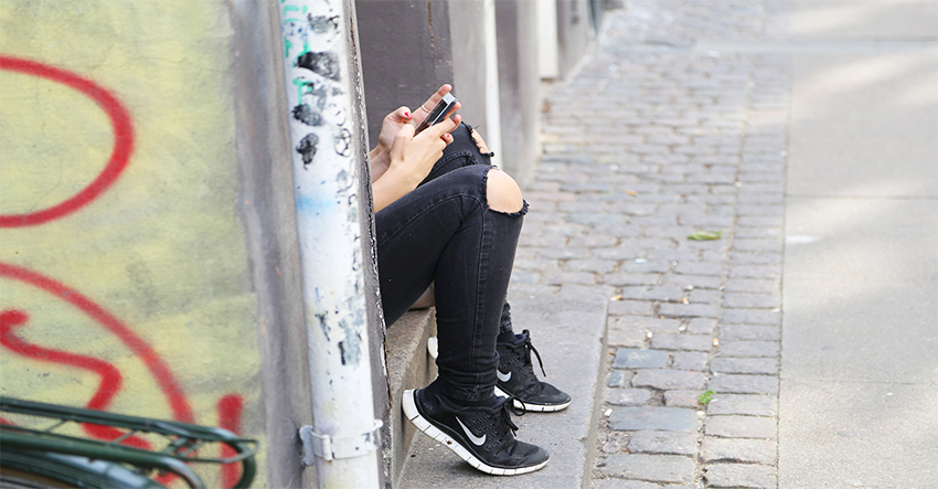 Tonåring sitter med mobil