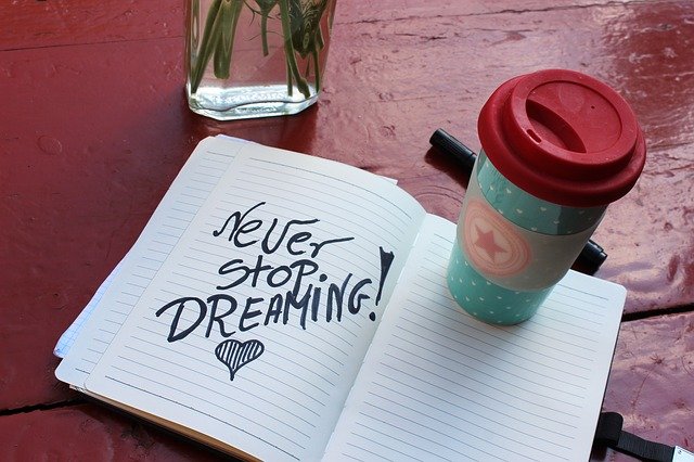 never stop dreaming står det på ett block jämte en kaffekopp