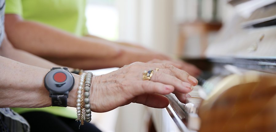 Äldre dam spelar piano tillsammans med en medarbetare på ett vård- och omsorgsboende