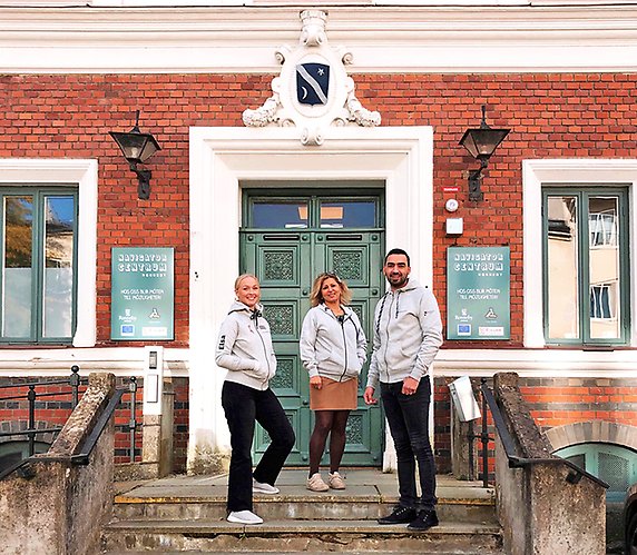 Tre personer står framför entrén till Navigatorcentrums nya lokaler i gamla Rådhuset i Ronneby. Elsa, (till vänster) receptionist, Muna (mitten) språkstöd och Hani administratör, hälsar besökare välkomna..